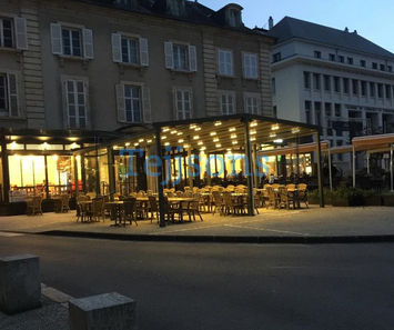 Outdoor restaurant terrace with a lit pergola at dusk