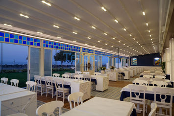 Modern restaurant pergola with retractable roof and lighting.