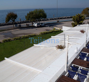 White retractable pergola overlooking a seaside promenade