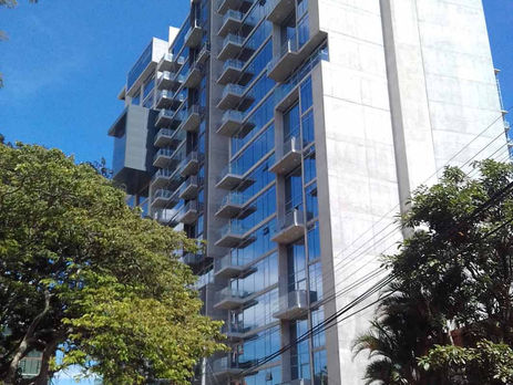 Vista de la fachada de QBO Skyhomes en Rohrmoser, destacando su posición frente a los espacios verdes y árboles del Parque del Café.