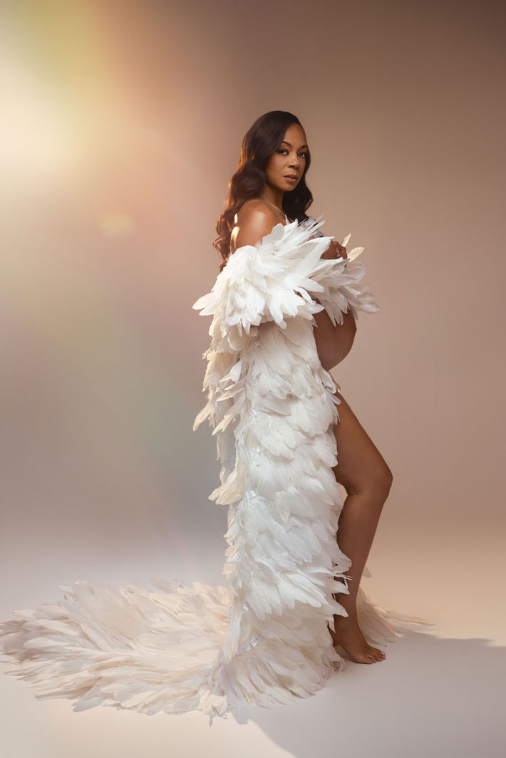 beautiful mom to be in feather outfit with golden hour at the studio