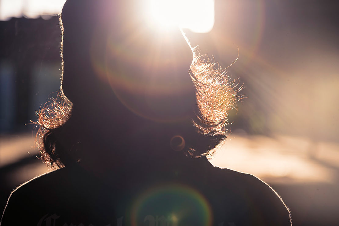 Juno, stands with the sun emanating from their head, embodying the creative energy and artistic vision associated with music production, video production, media production, and branding.