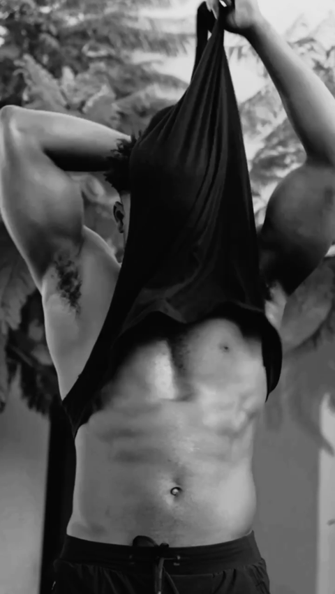 a black and white photo of a man taking off his shirt