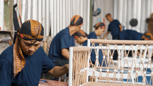 A man wearing a bandana is working on a chair for Dallas video production.