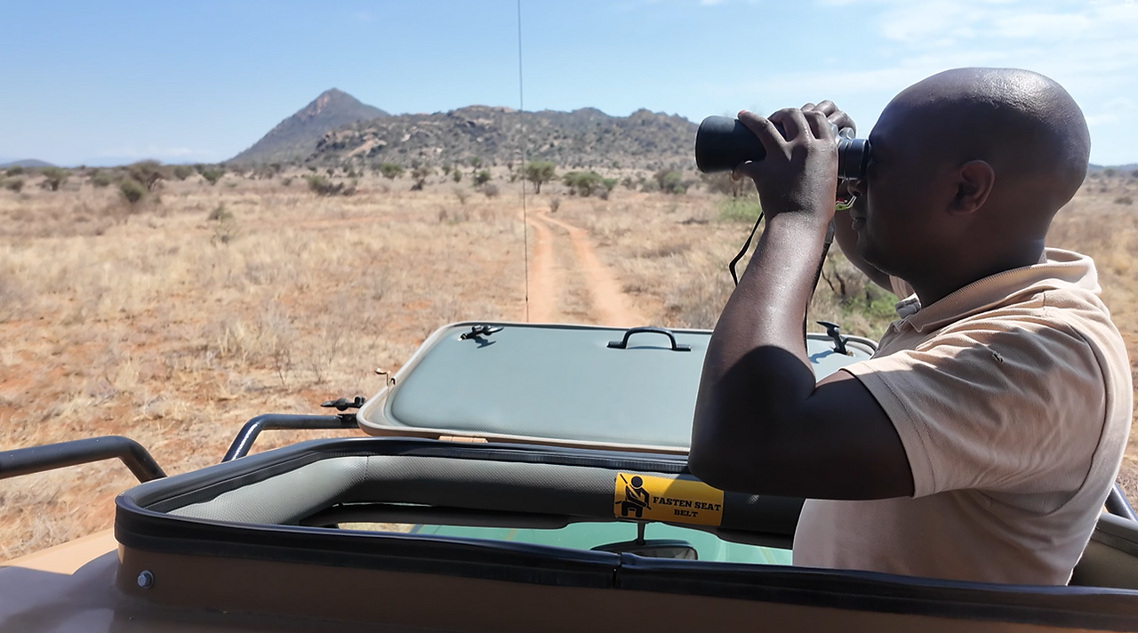 A safari driver, looks through his binoculars during a photographic safari in Samburu National Reserve.