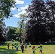Children in safety vests playing outdoors in a park.