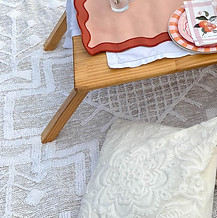 Low timber picnic table paired with white boho rugs and floor cushions on the Gold Coast