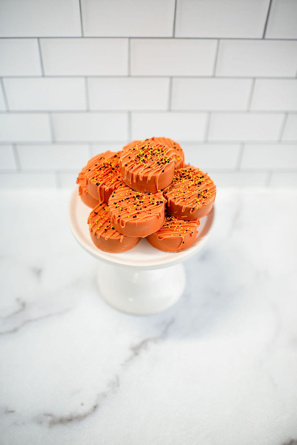 Pumpkin spice dipped flavored oreos on a small white cake stand