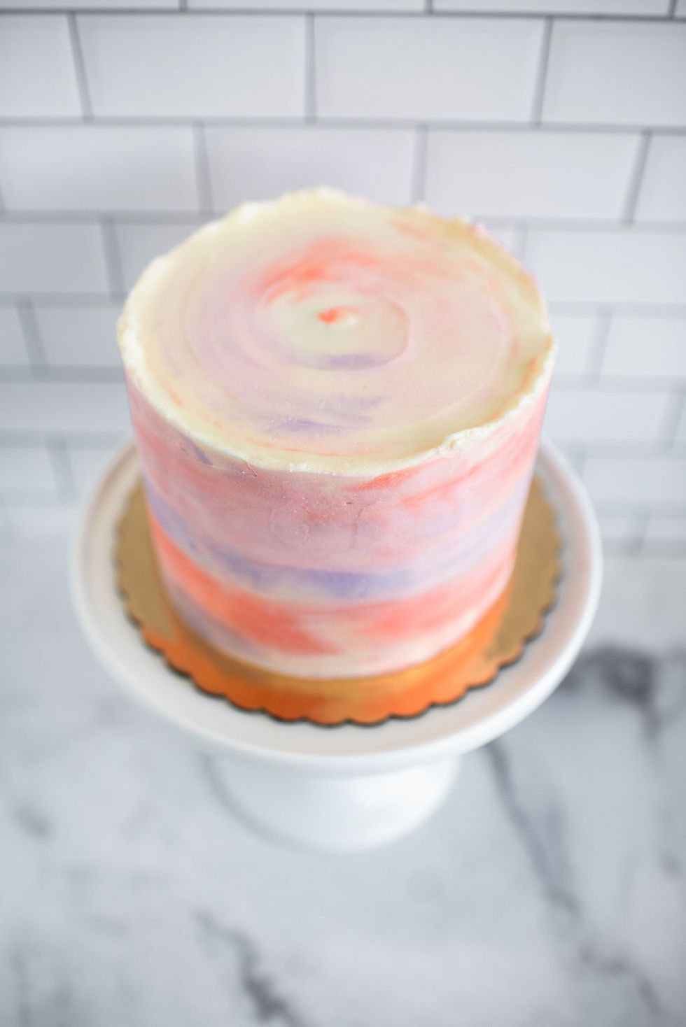 A soft and elegant cake design featuring a watercolor buttercream style in soft pastel colors