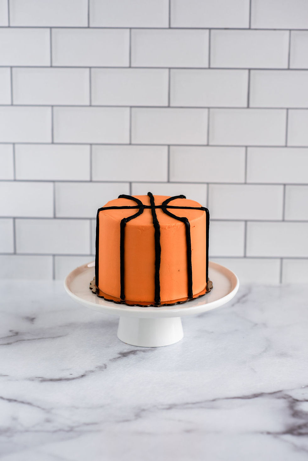 4-inch basketball-themed smash cake with orange buttercream and black piped lines.