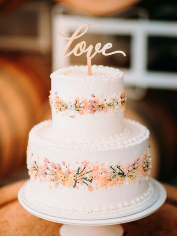 Wildflower themed wedding cake with a horizontal floral wreath wrapping around the center of each cake. Size is a large 2 tier cake. 