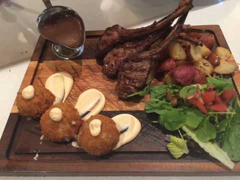 Beautiful lamb dish with delicious side dishes on a wooden table.