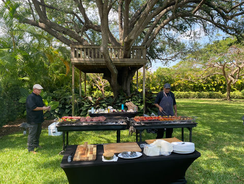Large barbecue grill in a beautiful garden with a tree behind.