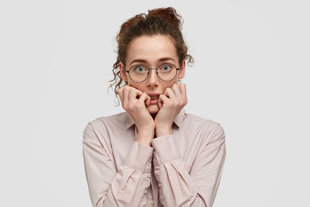 unhappy-nervous-young-female-with-worried-expression-bites-finger-nails-looks-anxiously-di
