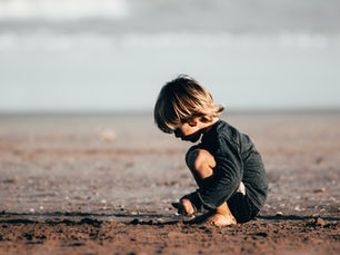 young boy playing by himself in the sand