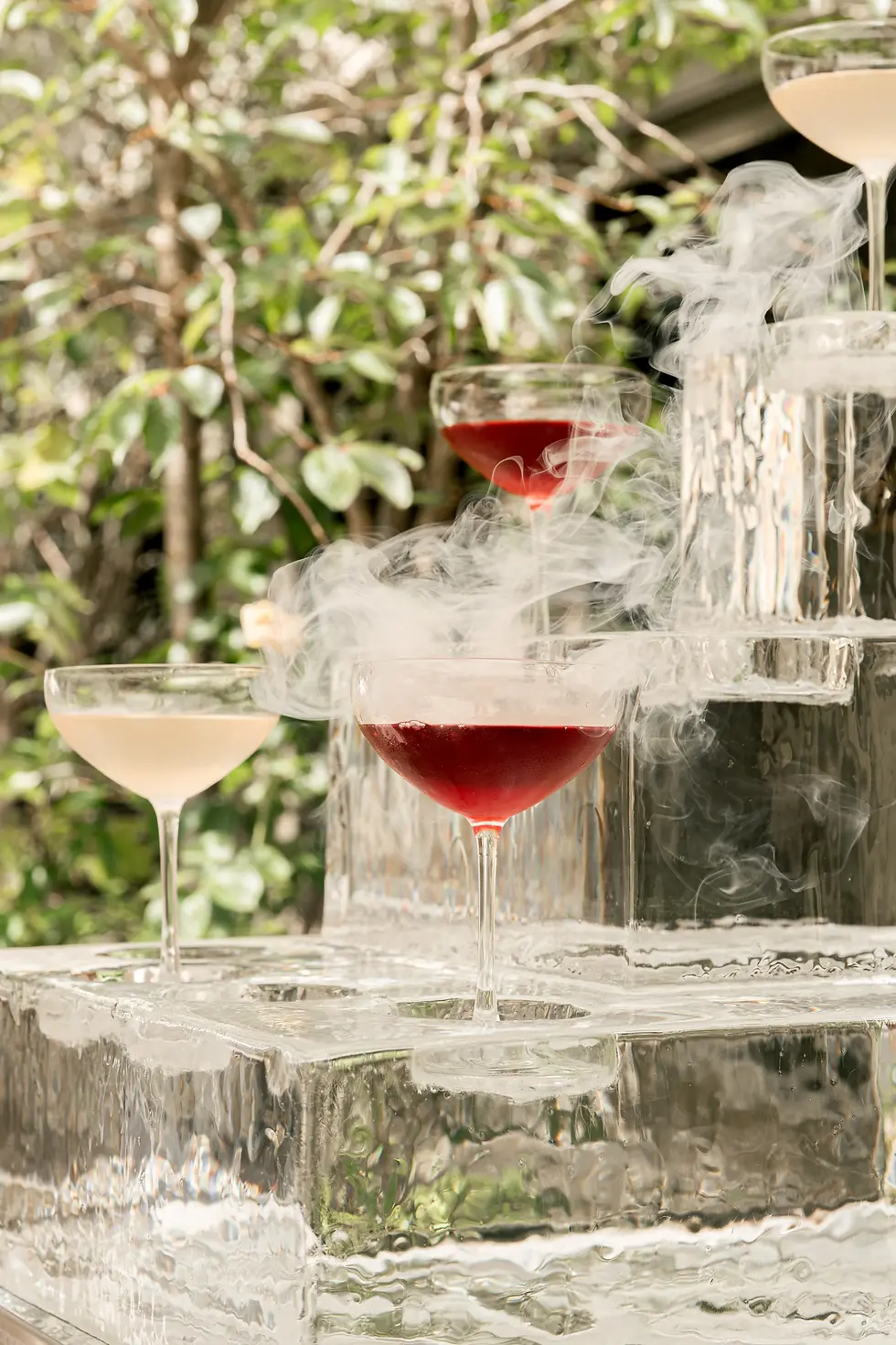 Cocktails fumés rouges et dorés présentés sur un bloc de glace