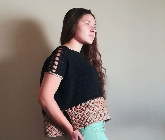 a woman wearing a crocheted drop-sleeve top with large eyelets on the shoulders and a woven pattern along the bottom.