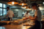 Wide-angle view of a busy restaurant kitchen during peak hours