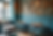 Cozy cafe with teal walls and vintage decor. Empty turquoise chairs around round tables. Sunlight streams in through windows, creating a calm mood.