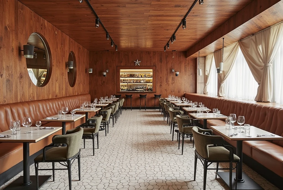 Wood-paneled restaurant with empty tables and chairs, brown leather benches, circular mirrors, and a lit bar in the background. Calm ambiance.