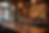 Elegant restaurant setting with a wooden table, wine glasses, bottle, and warm lighting. Shelves with bottles in the blurred background. Cozy mood.