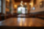 Wooden table in a cozy, warmly lit cafe with blurred chairs and wall art. Soft overhead lights create an inviting, serene atmosphere.