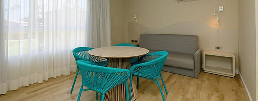 Sala de estar da Suíte Deluxe com mesa, cadeiras e sofá-cama