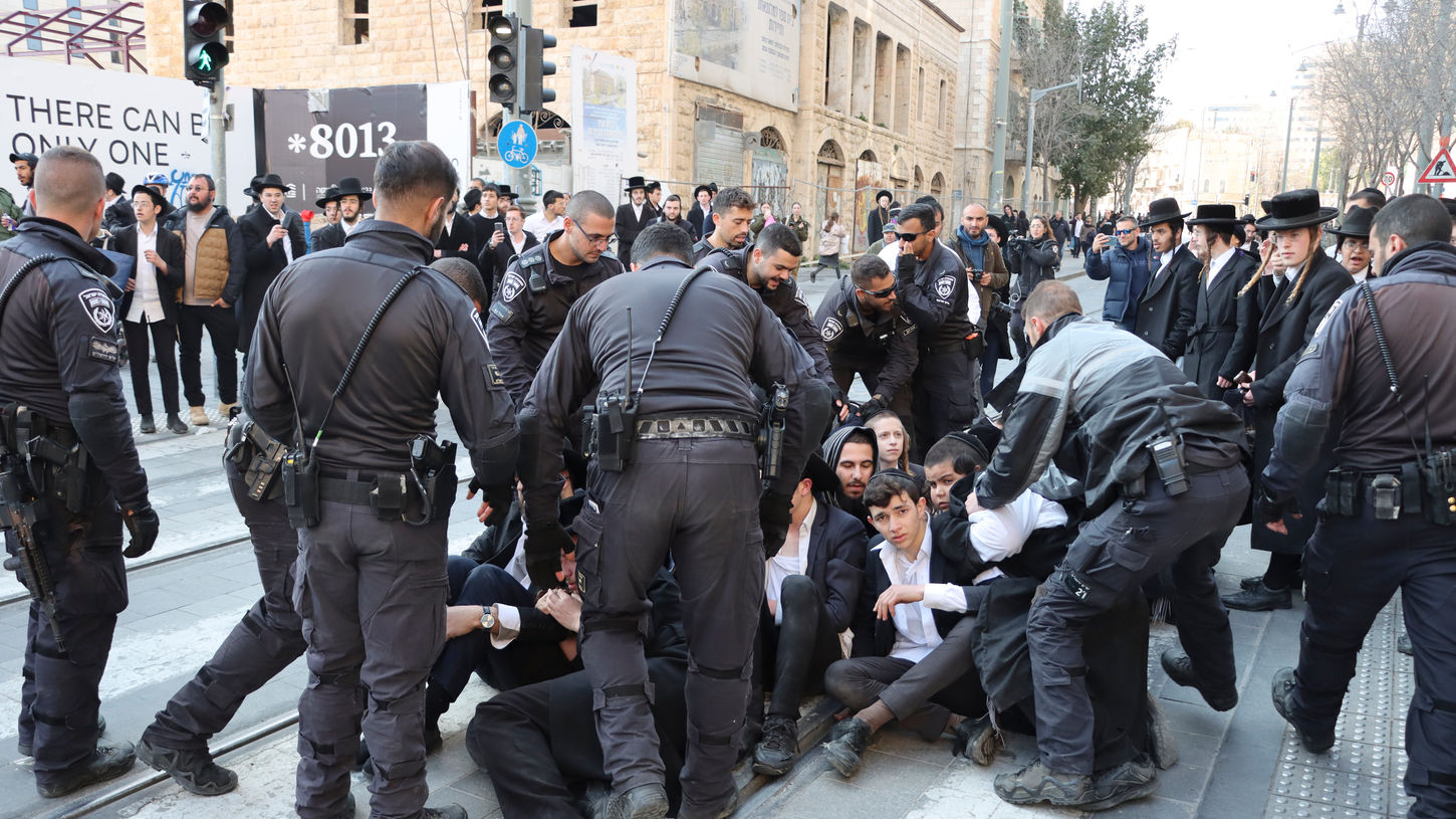 Ultra-Orthodox Jews protesting against an IDF draft and blocking the road are dragged onto the sidewalk by police in Jerusalem on Feb. 25, 2025.