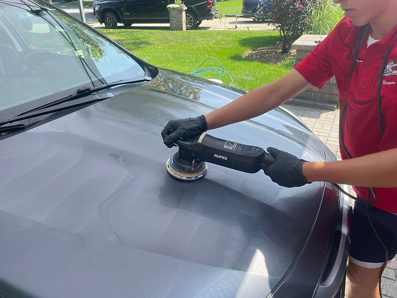 Auto detailer buffing the paint of an suv to remove scratches
