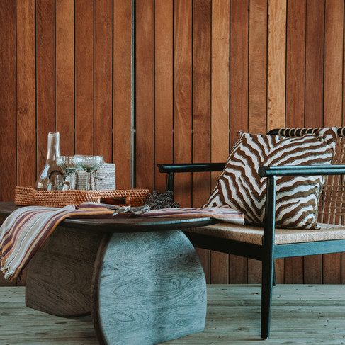 A sculptural black armchair styled with a striped pillow, highlighting modern design and cozy textures from the Atelier Fifty6 collection.