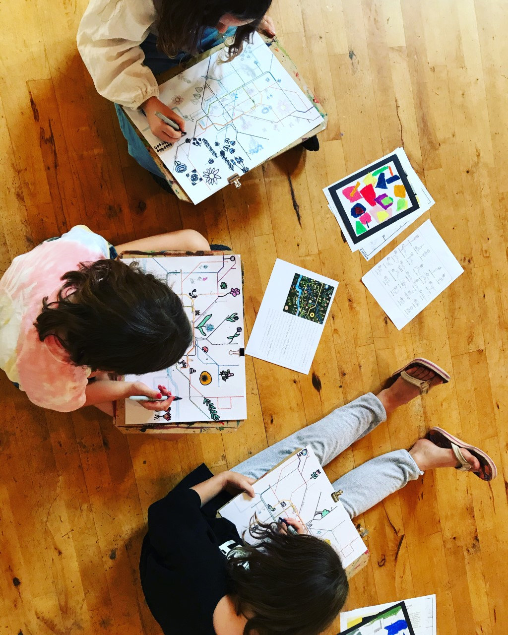 Overhead view of children sitting on the floor drawing with markers