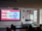 A photo of UnHerd Founder Oliver Snell stood up giving a lecture at De Montfort University 
