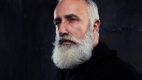 Close-up of a man wearing shirt and pullover, looking at camera against dark background. Man isolate