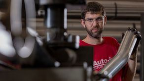 Auto-jet team member holding a bent stainless exhaust component