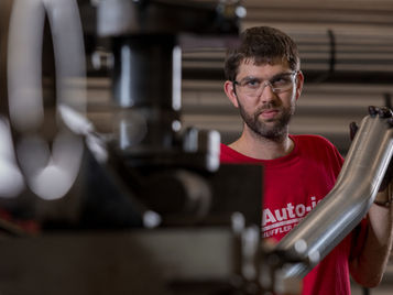 Auto-jet team member holding a bent stainless exhaust component