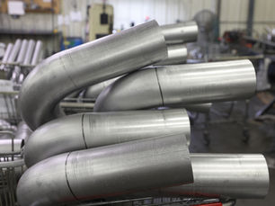 Finished bent tube assemblies staged on carts on the production floor at TEC, moving through process toward inspection