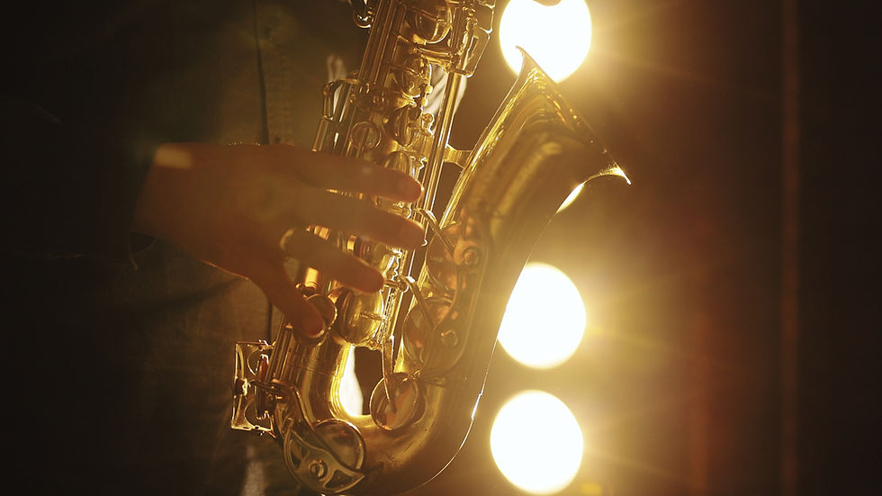 Hands playing a golden saxophone under warm stage lights, creating a dramatic and expressive mood.
