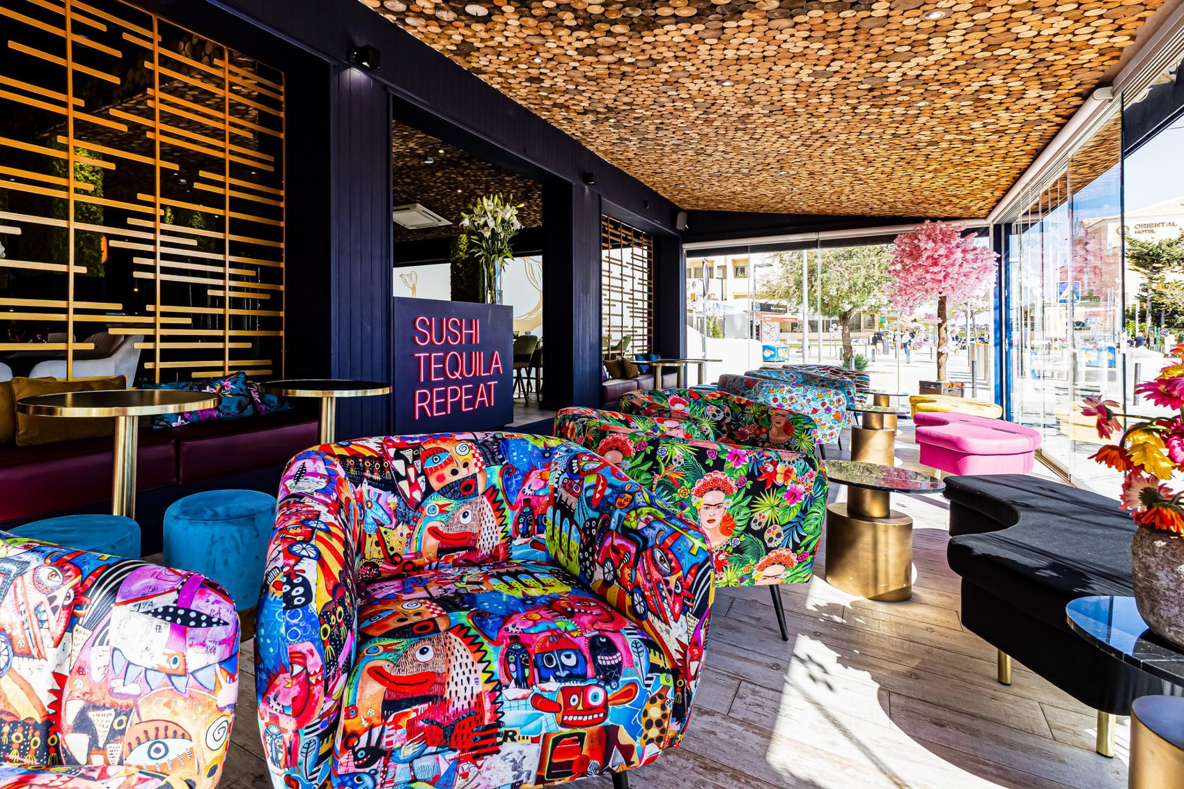 Lounge envidraçado do restaurante Nito, na Praia da Rocha, com cadeirões estampados e teto de rodelas de madeira