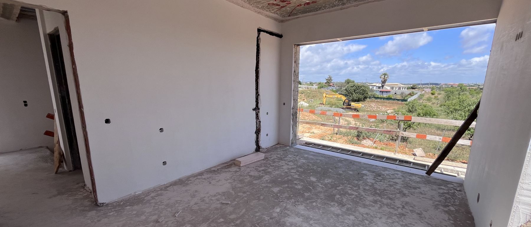 Interior de uma moradia em construção com o vão aberto sobre a paisagem