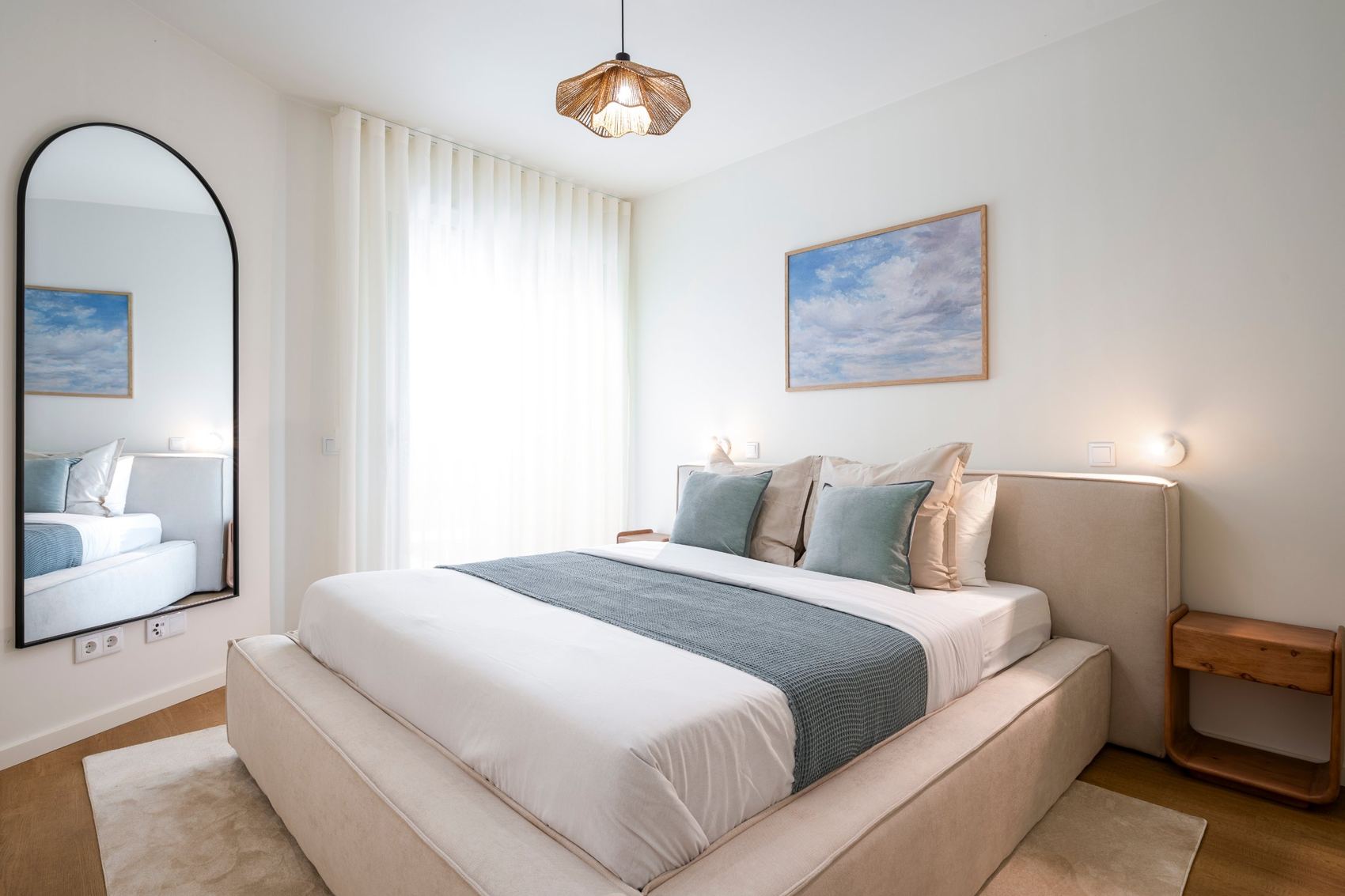 Quarto com espelho em arco e quadro de nuvens