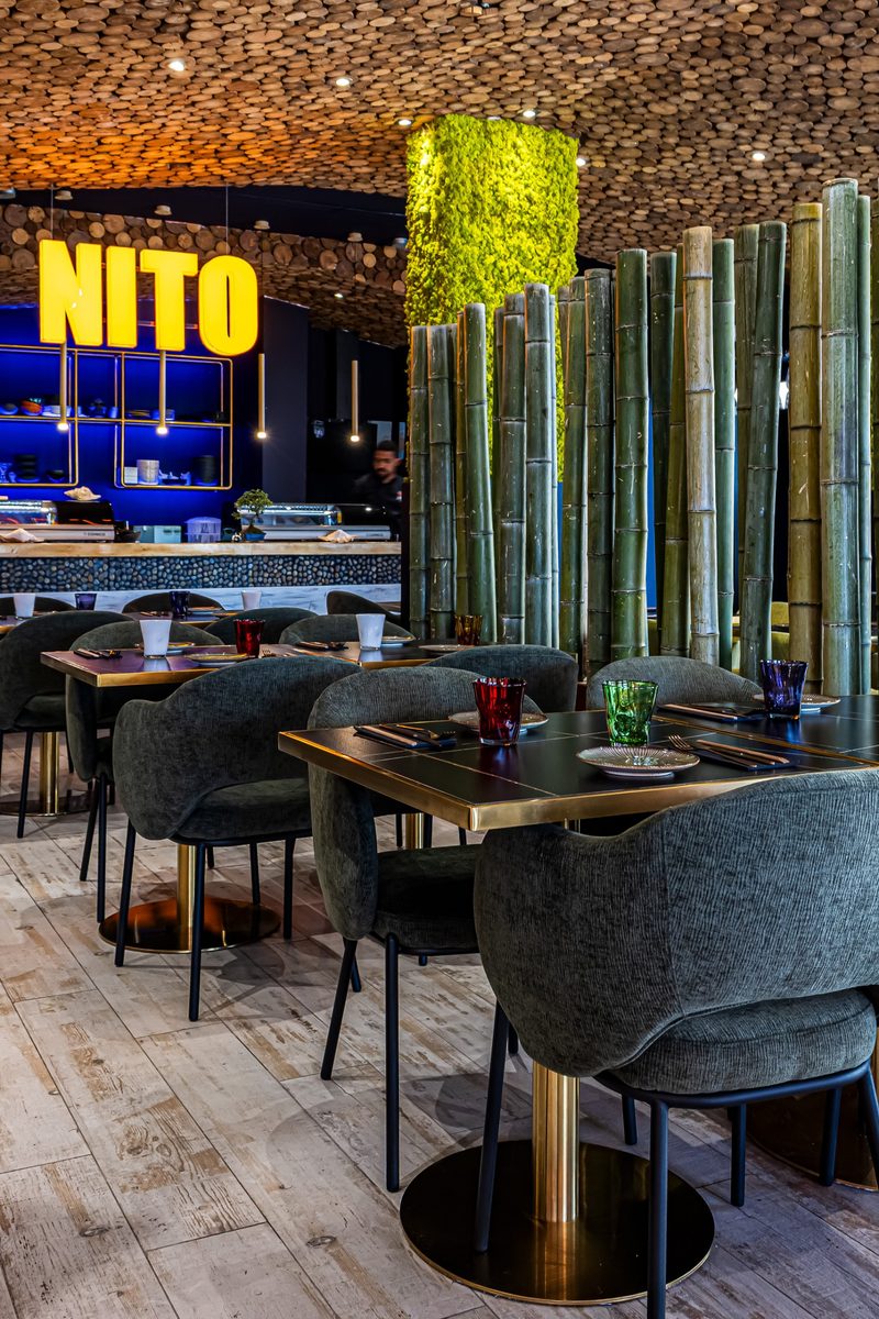 Sala principal com divisória de bambus, letreiro e balcão de sushi