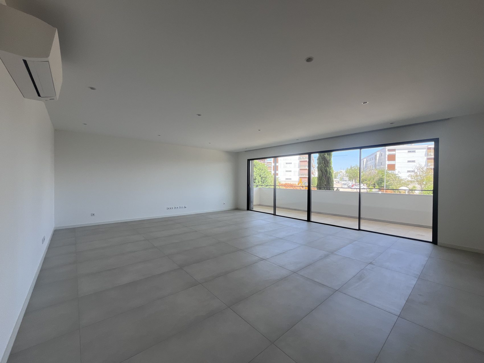 Sala vazia, eixo longo, vão envidraçado à direita