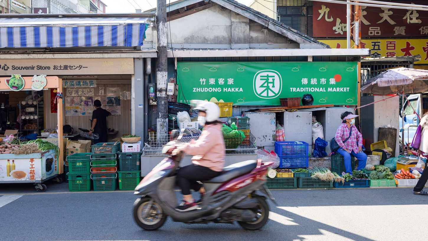竹東客家傳統市集入口品牌招牌,綠色橫幅搭配中英雙語標示與街景