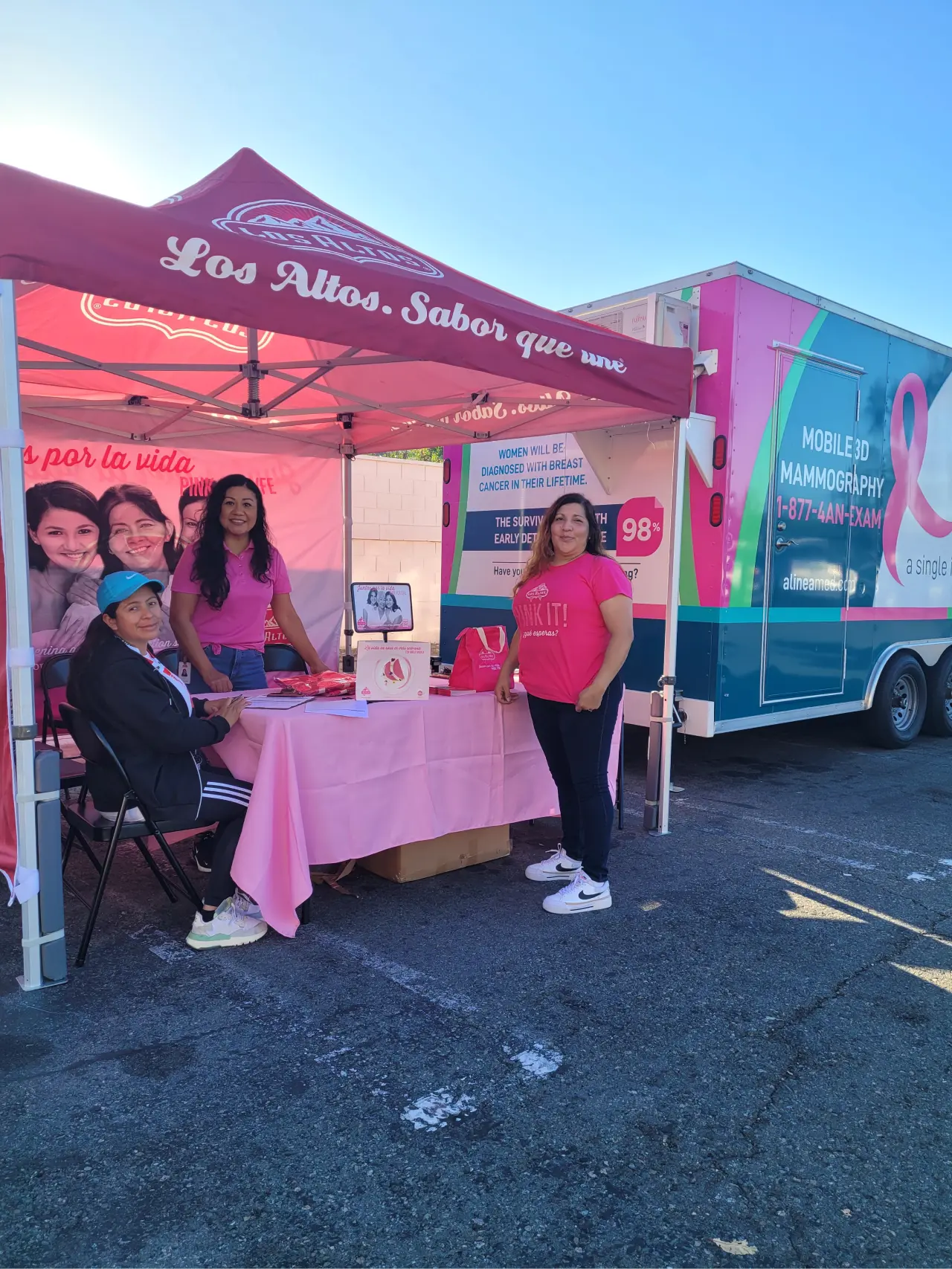 Heavy duty pop up canopy with Los Altos branding and breast cancer awareness table beside a mobile mammography unit.