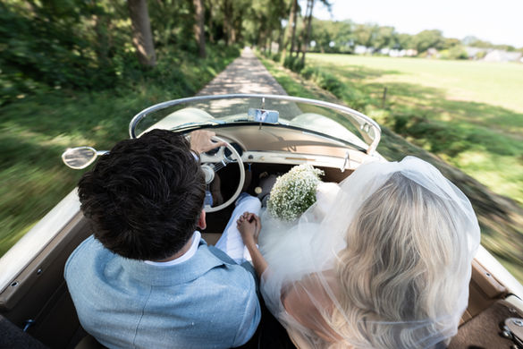 Bruidspaar samen in een klassieke cabriolet tijdens hun trouwdag