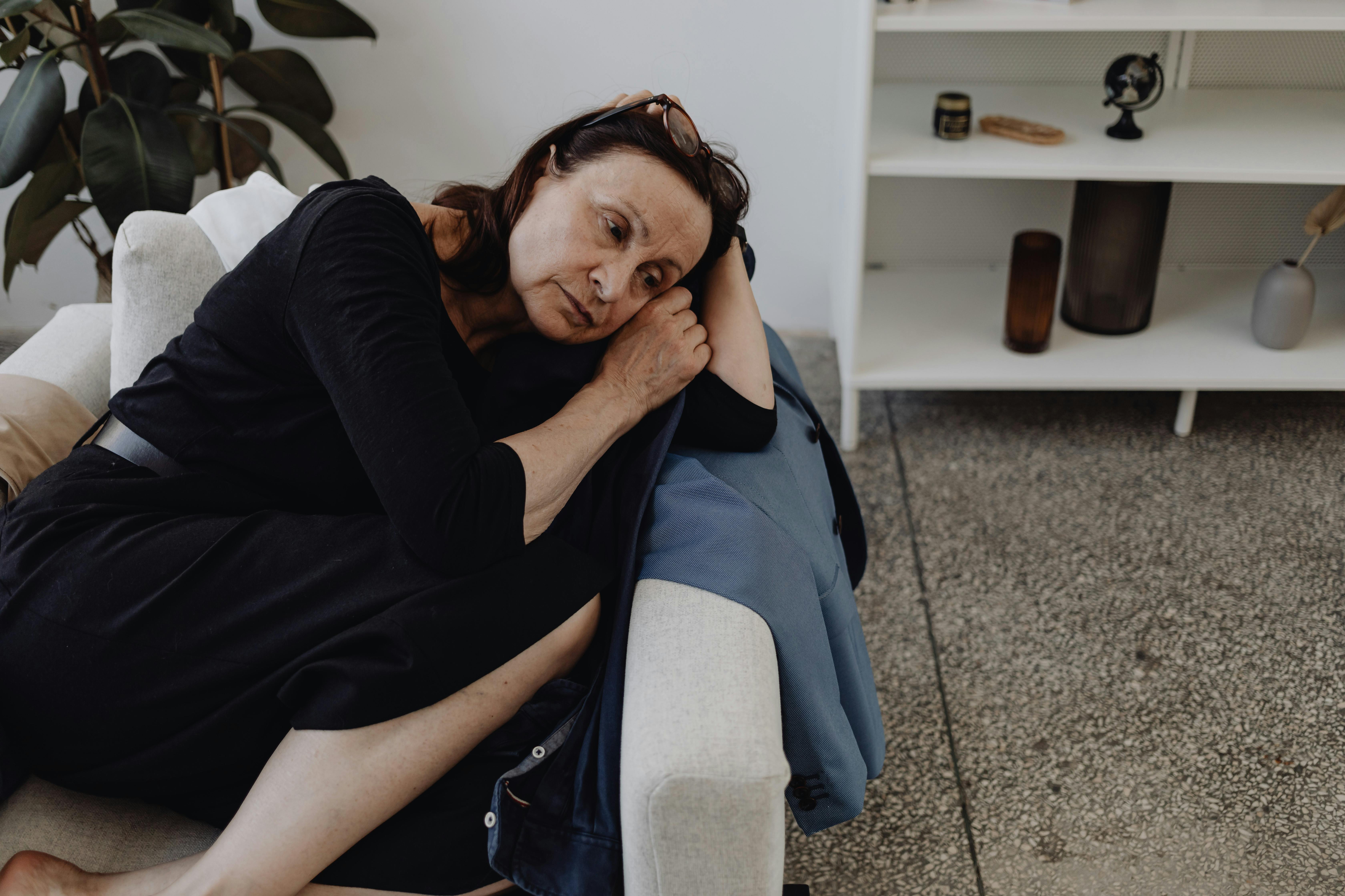a very tired woman, resting her head, culred up in a ball, looking distraught