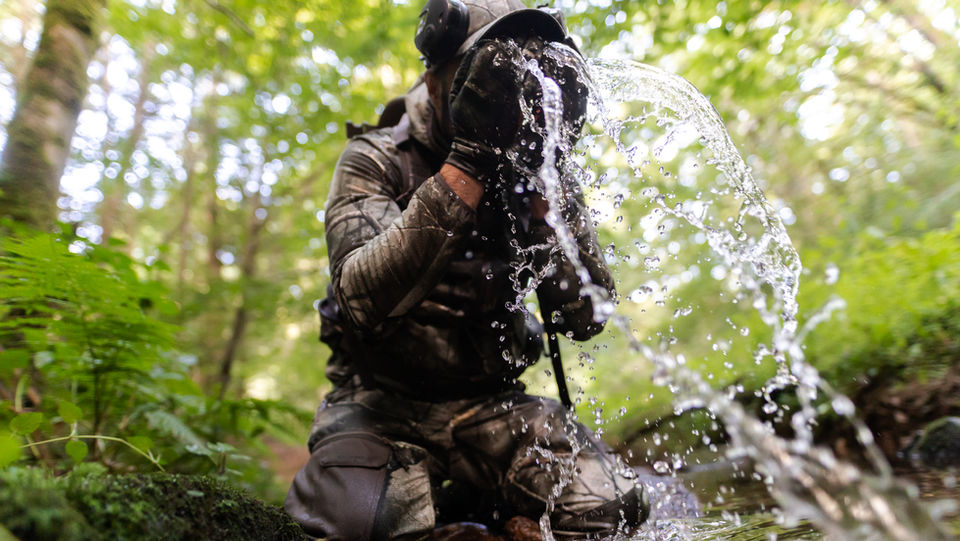 chasseur se rafraichissant au bord d'une rivière