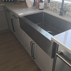 Clean stainless steel farmhouse sink and white cabinets.