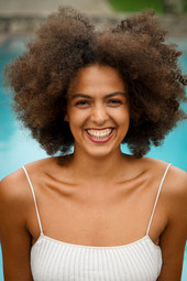 Lächelnde Frau mit Afro-Frisur lacht herzlich und offen in die Kamera