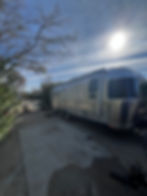 The Airstream is parked in a campsite